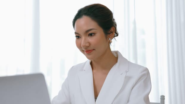 Young businesswoman sitting on the workspace desk using laptop computer for internet online content writing or secretary remote working from home. Vivancy