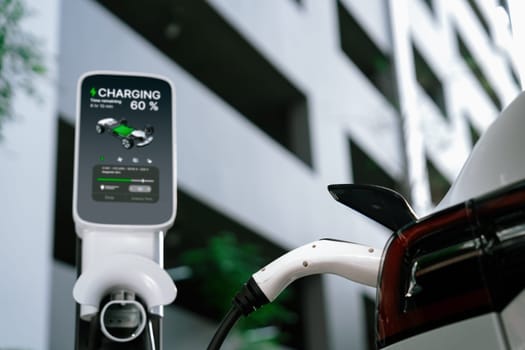EV electric car charging in green sustainable city outdoor garden in summer. Urban sustainability lifestyle by green clean rechargeable energy of electric BEV vehicle innards