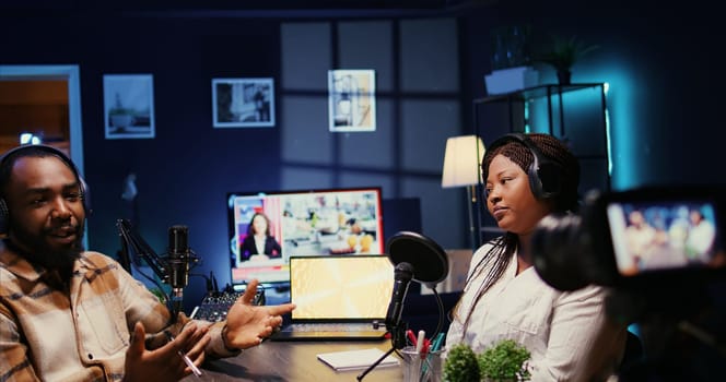 African american influencers in studio using high tech camera for internet show production on livestreaming channel. Vloggers partners doing podcasting session with professional video gear