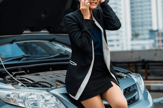 Young businesswoman whose car breakdown uses mobile phone to call for roadside assistance service. Travel and transportation vehicle problem. uds