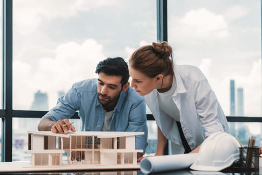 Smart caucasian architect engineer team working together to measure house model. Group of professional interior designer brainstorming and sharing ideas about design building construction. Tracery.