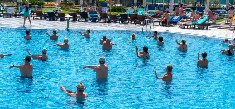 BUDVA, MONTENEGRO - SEPTEMBER 08, 2023: People of all ages join together for an aqua aerobics class in a hotel pool, embodying the spirit of group sports and fun. Concept of inclusive fitness and social interaction