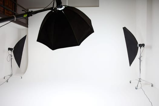 photo studio inside, white background, several racks with light sources, cyclorama, softboxes, pulsed light, flashes. High quality photo