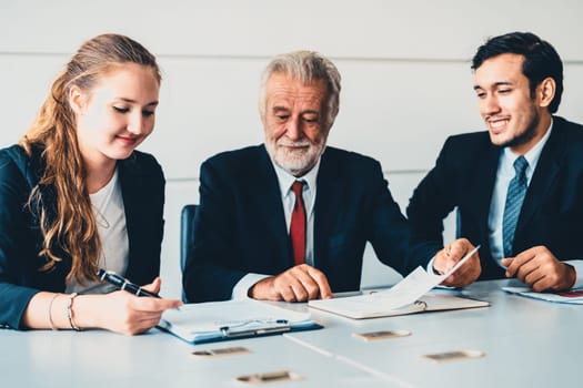 Senior old executive manager working with young businesspeople in office meeting room. Old man is company leader sitting with secretary and translator. International corporate business concept. uds