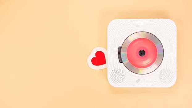 Heart shape gift card next to white cd player with red disc on yellow background. Love music, Valentine day, Greeting, retro Love song, space for text