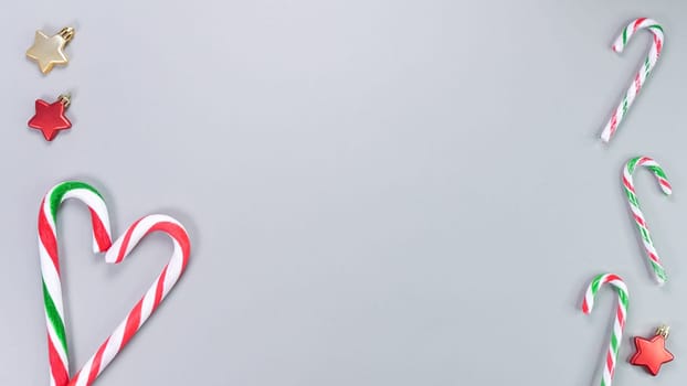 Christmas candy cane, golden and red stars, small and big candies on grey background. Christmas composition. Top view, flat lay.