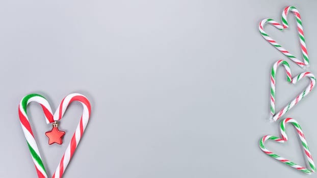 Christmas candy cane, golden and red stars, small and big candies on grey background. Christmas composition. Top view, flat lay.