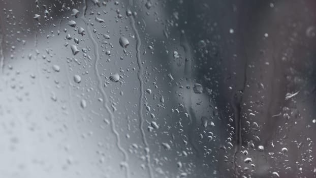 Macro of water drops on glass. Large rain drops strike window during winter shower. Pure rain drops