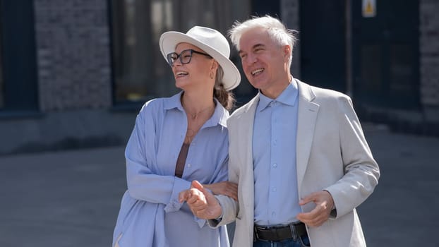 Stylish elderly laughing couple on a walk. Romantic relationships of mature people