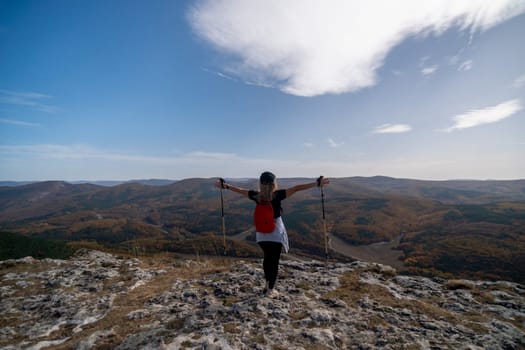 woman on mountain peak looking in beautiful mountain valley in autumn. Landscape with sporty young woman, blu sky in fall. Hiking. Nature.