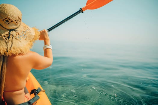 Woman in kayak back view. Happy woman with long hair in a swimsuit and hat floating in kayak on the sea. Summer holiday vacation. Summer holidays vacation at sea