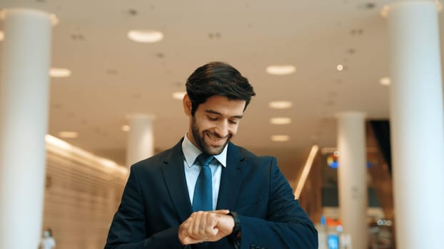 Caucasian smart business man looking at watch while waiting colleague. Executive manager wearing suit while standing at mall with blurred background. Investor wear blue suit check time. Exultant.