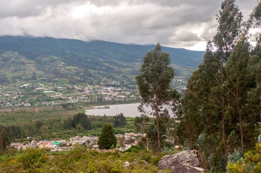 This photo captures a birds-eye view of a town and lake in Ecuador, offering a panoramic perspective of the landscape.