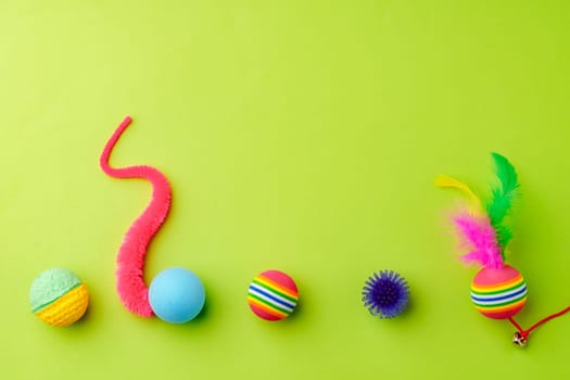 Colorful pet toys balls on green background close up