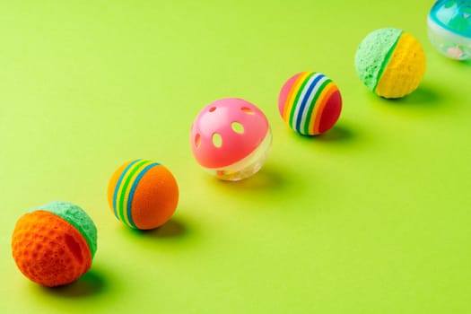 Colorful pet toys balls on green background close up