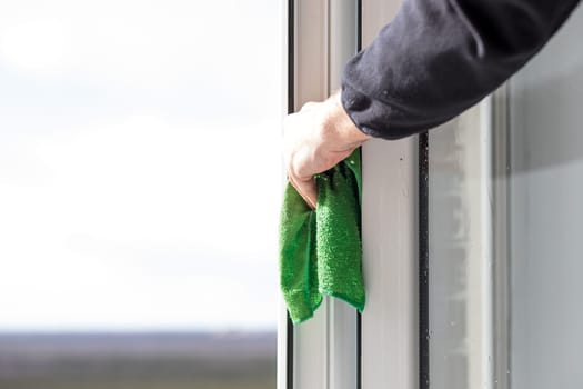 Cleaning windows with special rag and cleaner, male hands washes window glass in apartment house