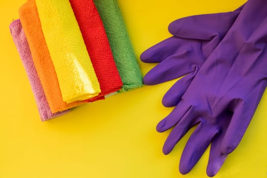 House cleaning products on yellow table. cleaning supplies.Rubber protective gloves and colorful microfiber cleaning cloths .