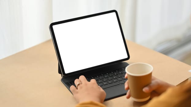 Female freelancer working on digital tablet at desk. Blank screen foe your advertising.