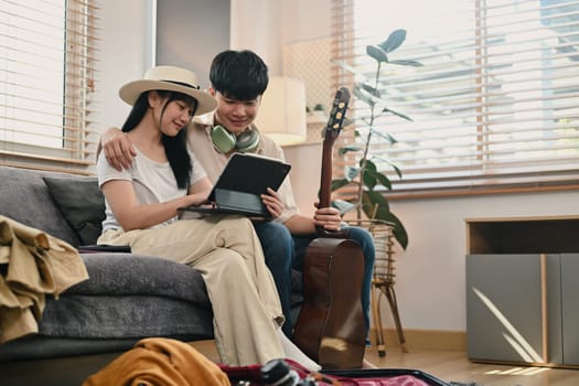 Attractive young couple using digital tablet for search travel trip online.