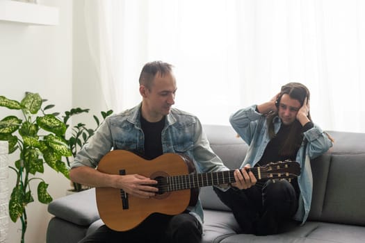 A father teaching his daughter how to play guitar. High quality photo