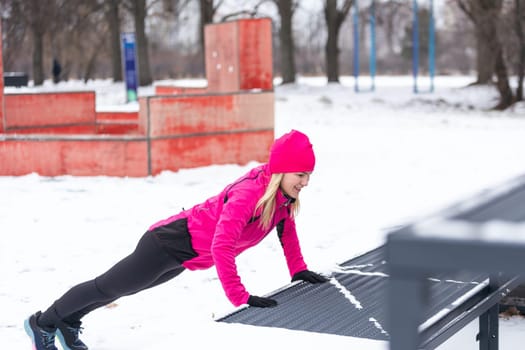 Workout in public park. Woman wearing warm sportswear urban street training exercising outside during winter. High quality photo