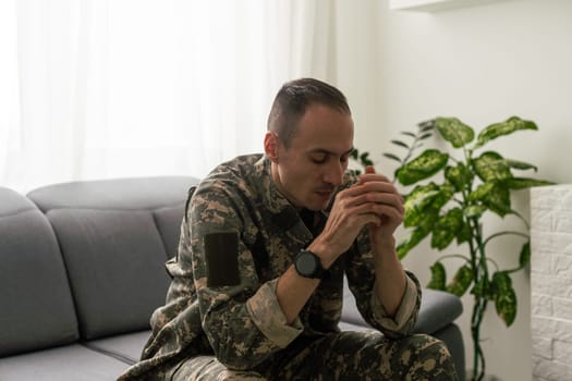 Depressed army man in uniform sitting in an empty room. Place for your poster on the wall. High quality photo