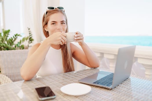 Woman coffee cafe macbook. Woman sitting at a coffee shop with mobile phone drinking coffee and looking away. Caucasian female relaxing at a cafe