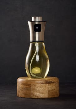 Glass transparent spray bottle filled with sunflower oil on a black table