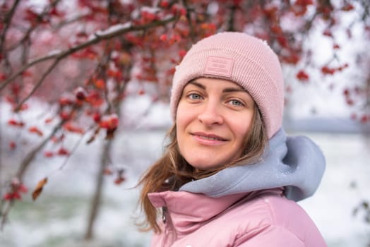 Winter lifestyle portrait of cheerful pretty girl. Smiling and having fun in the snow park. Snowflakes falling down.