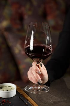 woman sitting at a table in a restaurant. He is holding a glass of red wine and eating a steak.