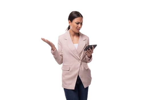 young confident caucasian woman with a ponytail hairstyle dressed in a jacket and jeans uses a smartphone in her hands.