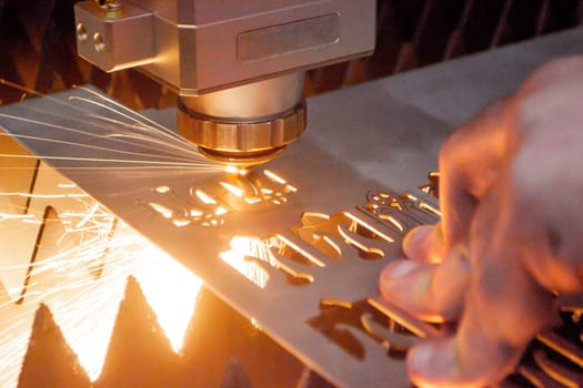 Metal laser cutting. Cutting sheet of metal by laser metal cutting close-up. Industrial equipment machine for cutting metal in factory. Moving head with sparks. Metalwork manufacturing background