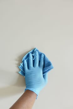 hand in blue rubber gloves cleaning table with towel .