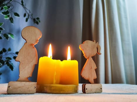 Wooden toys of boy and girl with yellow candles. Couple in love on Valentine's Day. Celebration of love and friendship. Card, background