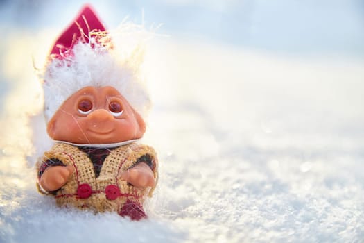 Cute little funny dwarf in the snow in the landscape in winter. Wizard on a snowy background. Christmas and New Year