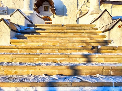 Steps of the staircase illuminated by the sun near the building in winter with snow. Slippery dangerous stairs. Background, pattern, abstract
