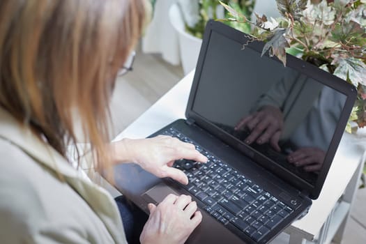 The hands of an elderly woman on a laptop keyboard. The lady communicates, works, studies on the Internet online. A businesslike old lady in a modern gadget