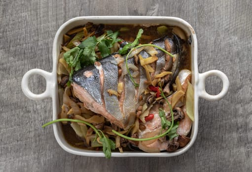 Thai-Chinese style Steamed Salmon with Soy Sauce and Ginger. ingredient include onion, ginger, mushrooms, red chilli, coriander and light soy sauce, Homemade food, Top view, Copy space, Selective focus.