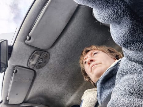 Portrait of female driver in solo journey. Adult mature woman holding steering wheel and looking through windscreen in travel by vehicle on vacation. Lady girl who is owner or rent car for travel