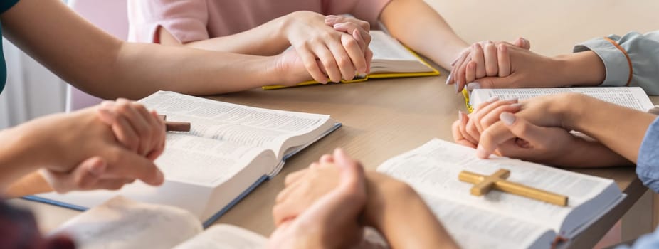 Cropped image of diversity people hand praying together at wooden church on bible book while hold hand together with believe. Concept of hope, religion, faith, god blessing concept. Burgeoning.