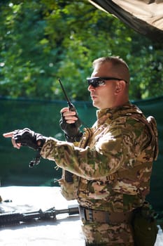 A military major employs a Motorola radio for seamless communication with his fellow soldiers during a tactical operation, showcasing professionalism and strategic coordination.