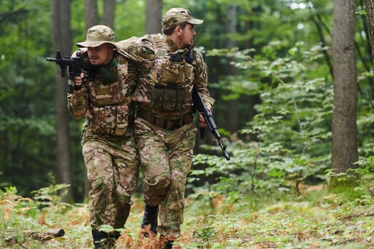 Elite soldier displays unwavering camaraderie and compassion as he aids his injured comrade, skillfully extracting him from the forest with a stretcher, showcasing the profound bond and selflessness within their military brotherhood.