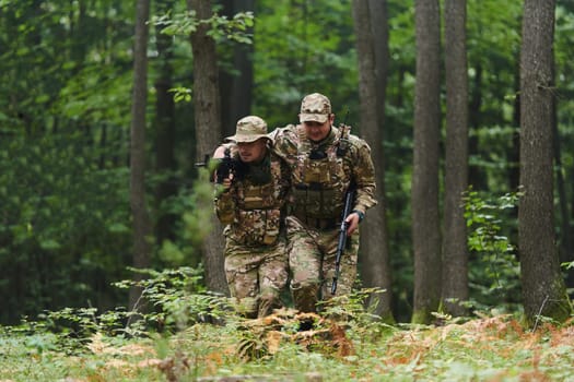 Elite soldier displays unwavering camaraderie and compassion as he aids his injured comrade, skillfully extracting him from the forest with a stretcher, showcasing the profound bond and selflessness within their military brotherhood.