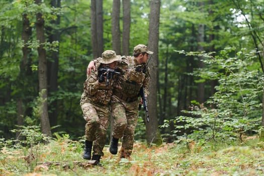 Elite soldier displays unwavering camaraderie and compassion as he aids his injured comrade, skillfully extracting him from the forest with a stretcher, showcasing the profound bond and selflessness within their military brotherhood.