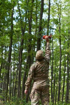 Elite military unit, equipped with state-of-the-art technology including a drone, strategically navigates and surveys dangerous wooded terrain, showcasing their precision, cooperation, and specialized training for high-risk operations.