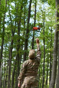 Elite military unit, equipped with state-of-the-art technology including a drone, strategically navigates and surveys dangerous wooded terrain, showcasing their precision, cooperation, and specialized training for high-risk operations.