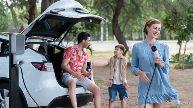 Family road trip vacation with electric vehicle, lovely family recharge EV car with green and clean energy. Natural and eco friendly car travel for sustainable environment. Perpetual