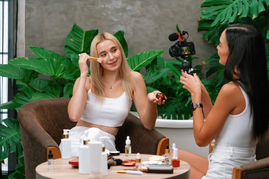 Two beautiful content creator making natural beauty and cosmetic tutorial on green plant garden video. Beauty blogger showing how to beauty care to social medial audience using selfie stick . Blithe