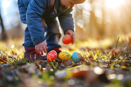 A small toddler gathering colorful Easter eggs on a bright sunny day in the autumn leaves.