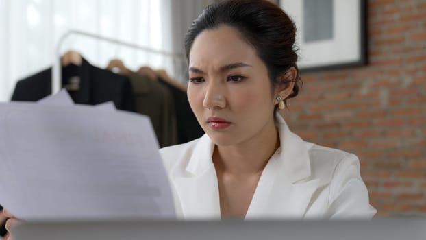 Young businesswoman sitting on the workspace desk using laptop computer for internet online content writing or remote working from home. Clothing and textile business marketing analysis. Vivancy